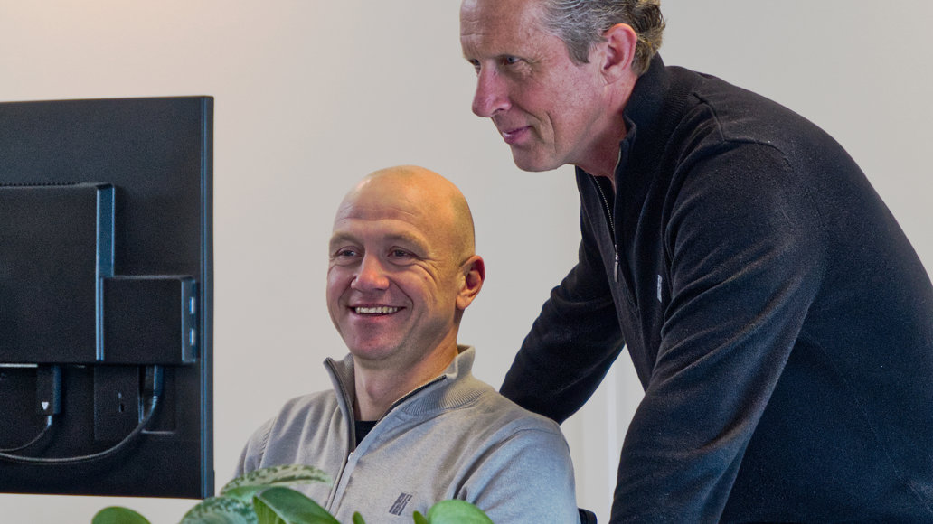 twee mannen lachend kijkend naar een computerscherm