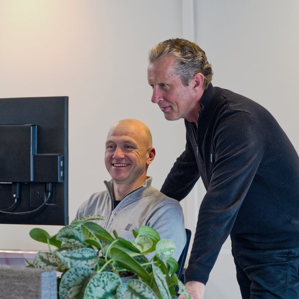 twee mannen lachend kijkend naar een computerscherm