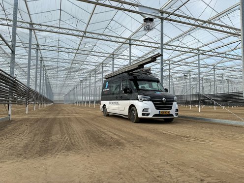 zwart witte werkbus in kas in aanbouw op losse grond