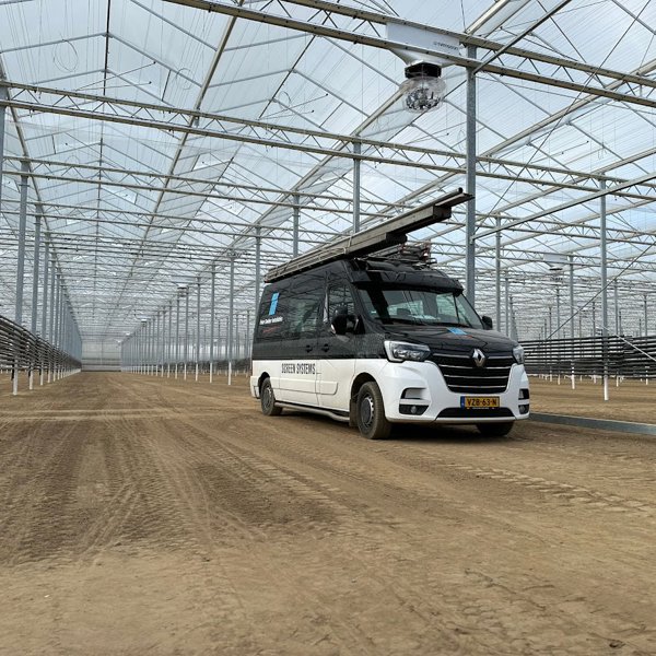zwart witte werkbus in kas in aanbouw op losse grond