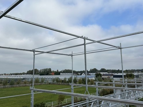 stalen kasconstructie van een kas in aanbouw met vergezicht over weiland en kassen