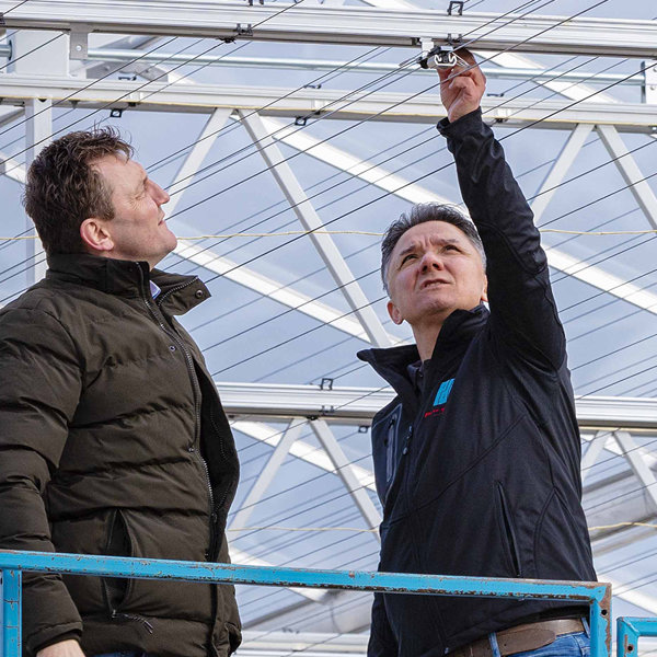 twee mannen wijzend naar een schermconstructie in een kas