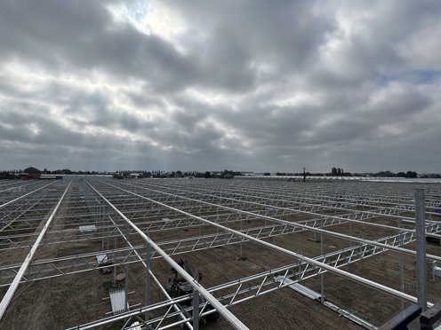 stalen kasconstructie van een kas in aanbouw met vergezicht over kassen