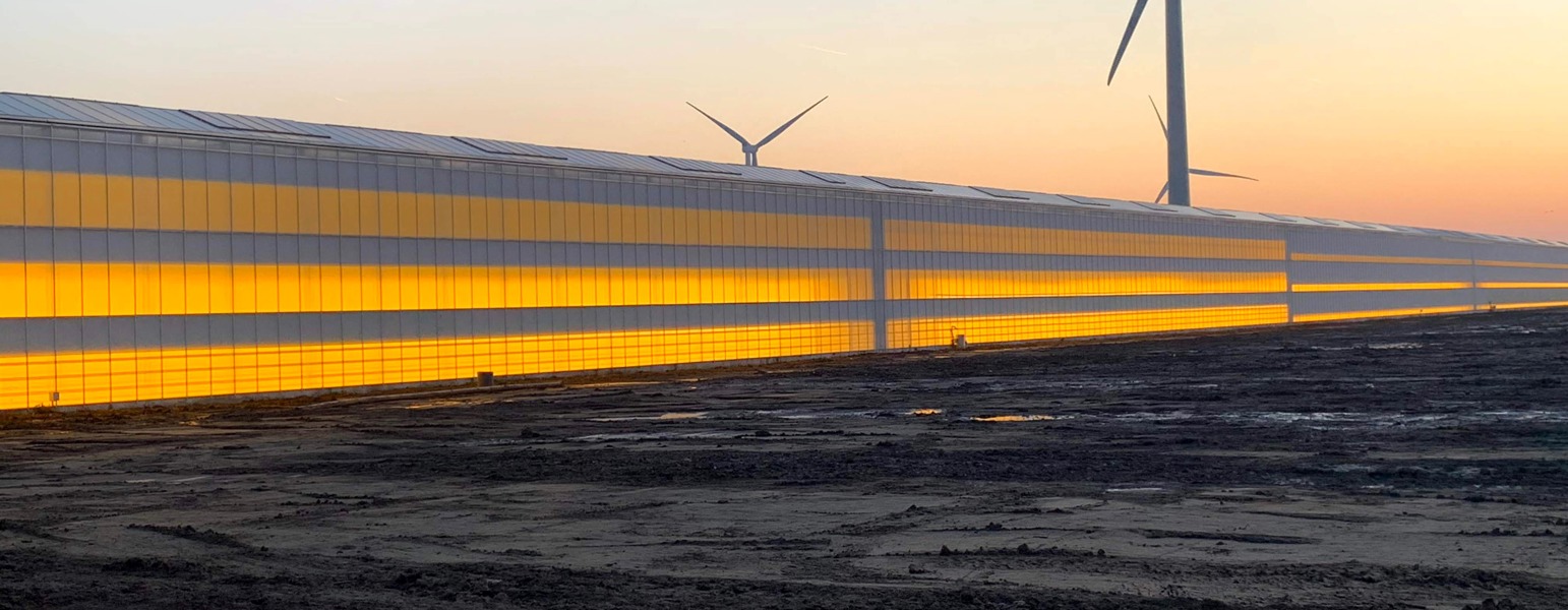 kas in schemer met lampen aan en windmolen op achtergrond