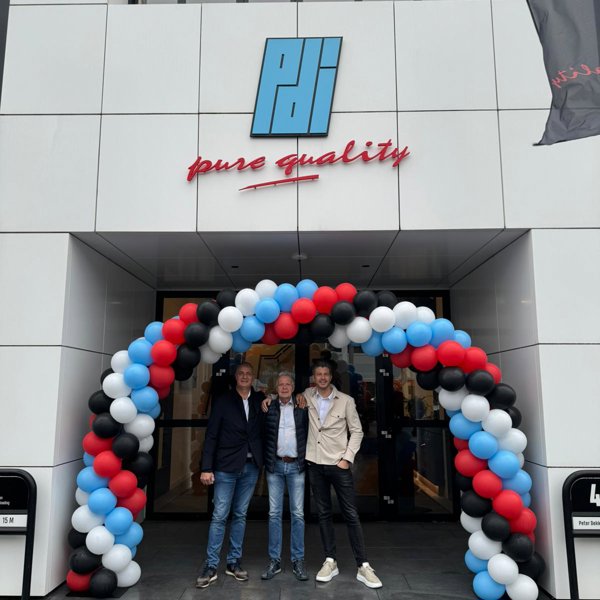 balloon arch in black blue and white with three happy-looking men in front of the entrance of a building