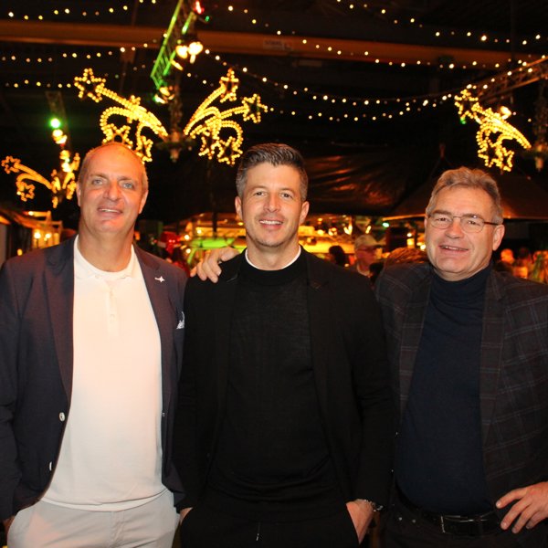 drie blije mannen in een feestelijk aangeklede zaal