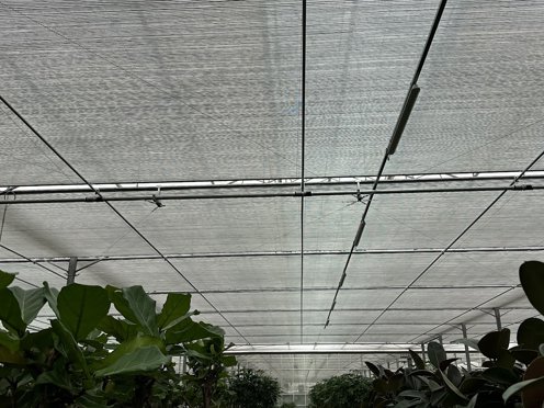 schermdoeken in de nok van een kas vol groene planten