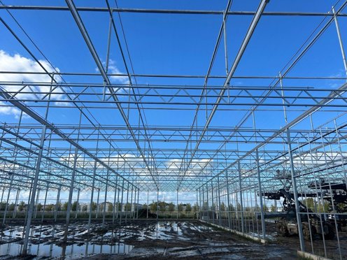 kas in aanbouw in de zon met modder ondergrond