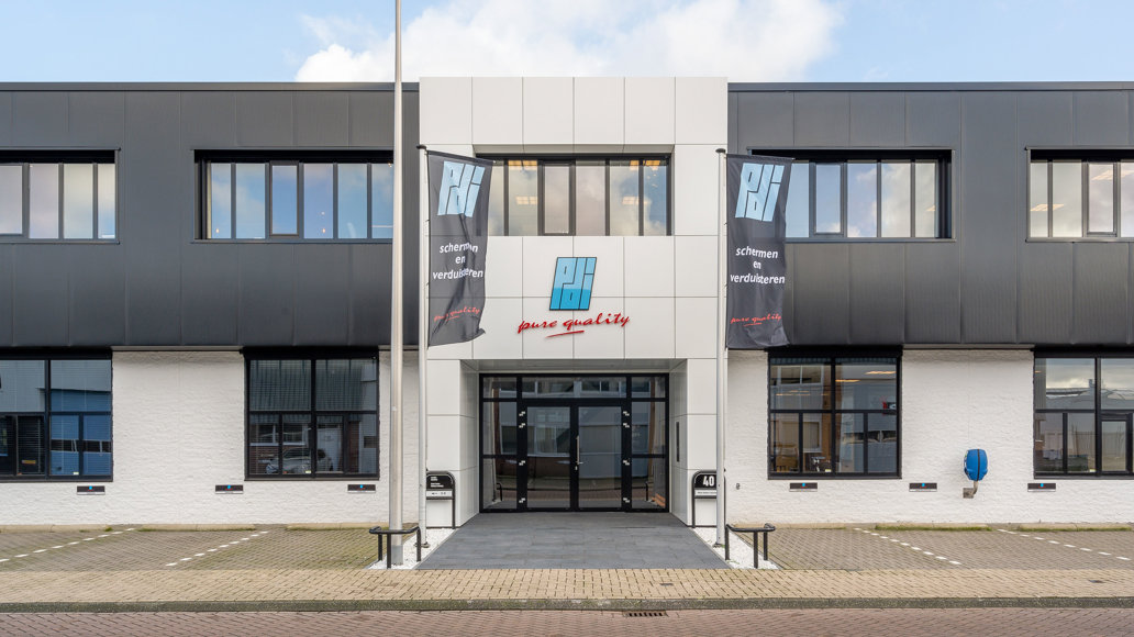 straataanzicht zwart wit kantoor PDI met wapperende vlaggen