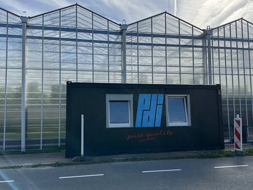 tuinbouwkas met een zwarte werkcontainer ervoor