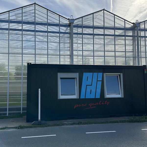 tuinbouwkas met een zwarte werkcontainer ervoor