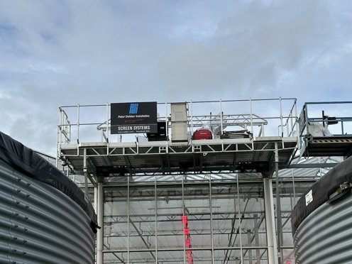 servicerail aan een kas bevestigd gefotografeerd tussen twee silo's in 
