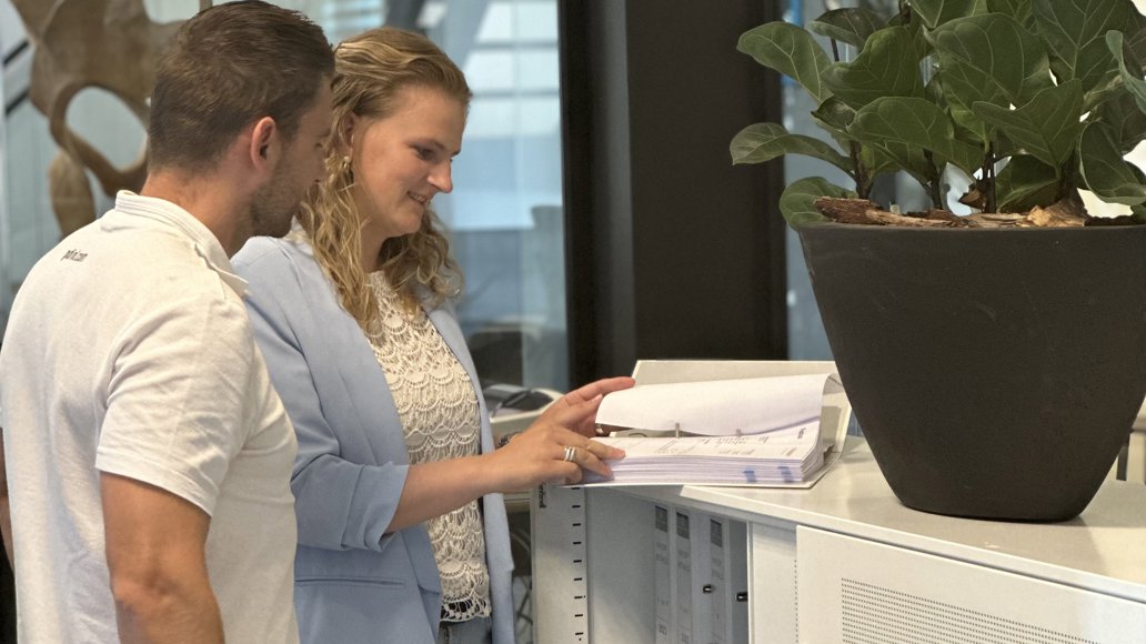 man en vrouw bladerend in een map op kantoor