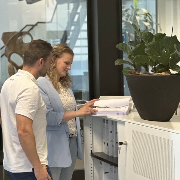 man en vrouw bladerend in een map op kantoor