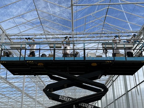4 mannen op een hoogwerker aan het werk in kas in aanbouw