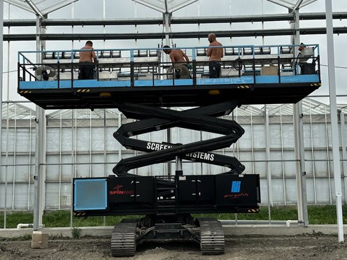 drie mannen op een hoogwerker in een kas aan het werk
