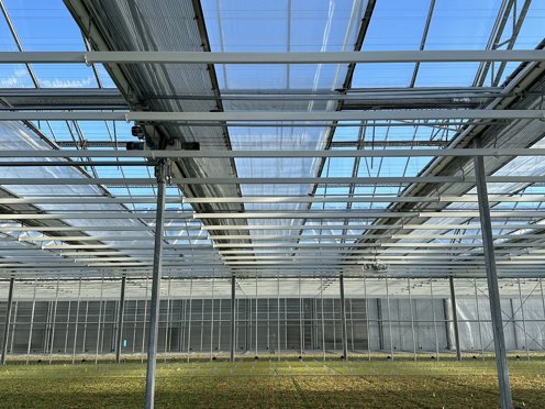 groen gewas in een tuinbouwkas met half gesloten schermdoeken op een zonnige dag