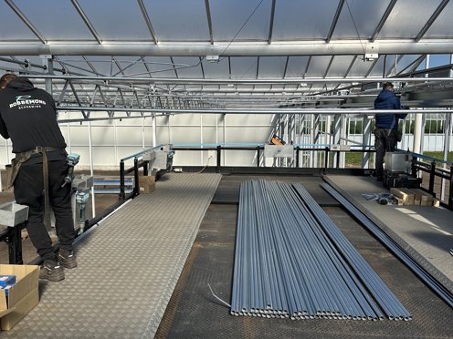 twee mannen in de nok van een kas installeren schermdoeken