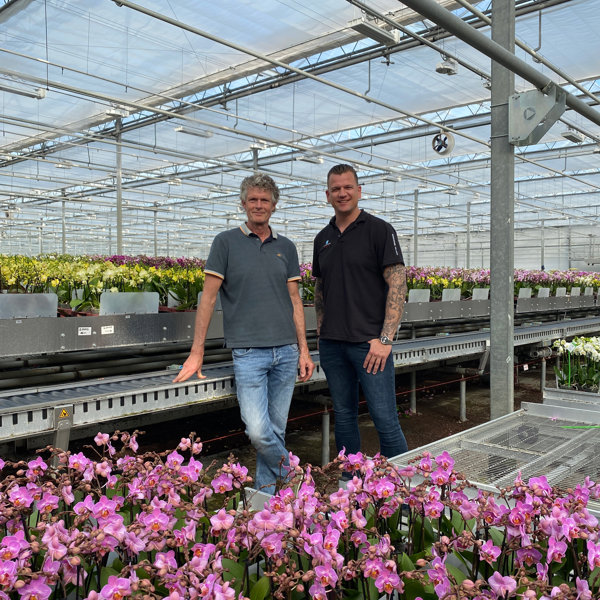 twee blije mannen in kas met orchideeën 