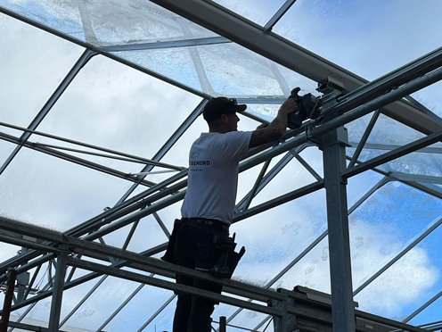 man hoog in kas installeert schermdoek