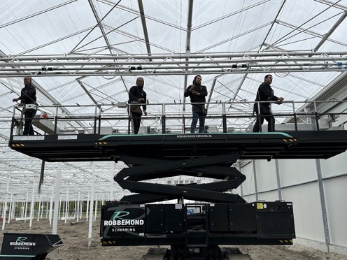 hoogwerker in kas in aanbouw met vier mannen