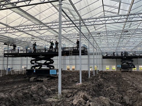 mannen op twee hoogwerkers installeren schermdoeken in kas in aanbouw