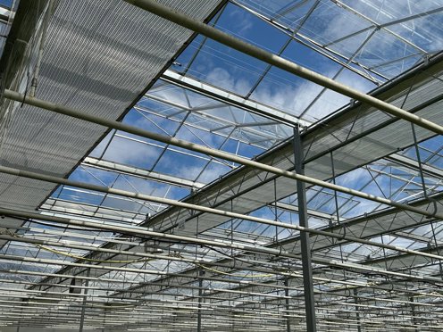 horizontale schermen in een glaskas die half open zijn op een zonnige dag