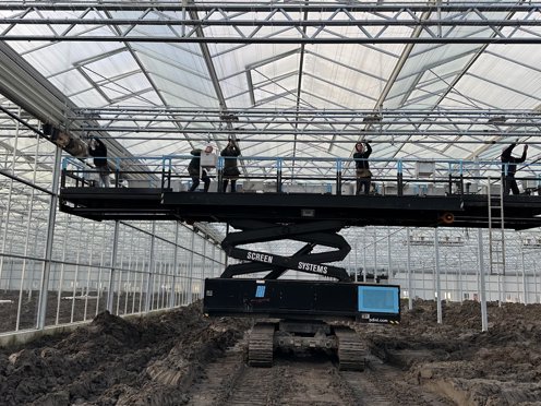 mannen op hoogwerker installeren schermdoeken in kas in aanbouw
